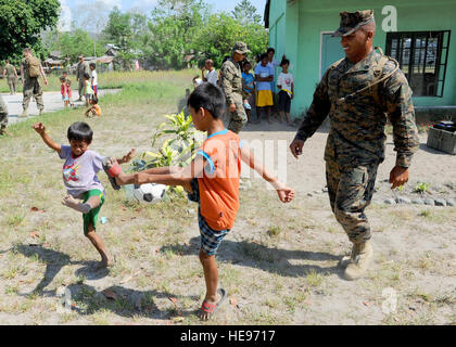 U.S. Marine Staff Sgt. Bakhit McBride, a Seattle native and utility chief with 9th Engineer Supply Battalion, 3rd Marine Logistics Group, III Marine Expeditionary Force, plays soccer with two students from Maruglo Elementary School in Crow Valley, Philippines, April 12 during ongoing community relations events at Balikatan 2013, an annual Philippine-U.S. bilateral exercise. Humanitarian assistance and training activities enable the Philippine and U.S. forces to build lasting relationships, train together and provide assistance in communities where the need is the greatest. Tech. Sgt. Jerome S. Stock Photo