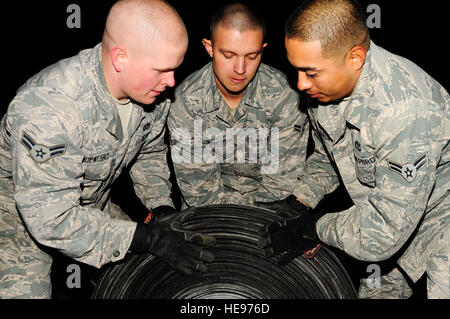 U.S. Air Force Airman 1st Class Isaac Vandeweert, from Harford, N.Y., Spencer Thresh, from Port Orchard, Wash.,  and Airman 1st Class Richard Ojeda III, from Texas, prepare aircraft arresting tape for transport as part of the replacement process on Kadena Air Base, Japan, Dec. 6, 2013. Cutting the old tape allows the barrier maintenance Airmen to roll the tape into groups and easily remove it from the flightline. They are assigned to 18th Civil Engineer Squadron electrical power production section.  Staff Sgt. Darnell T. Cannady) Stock Photo