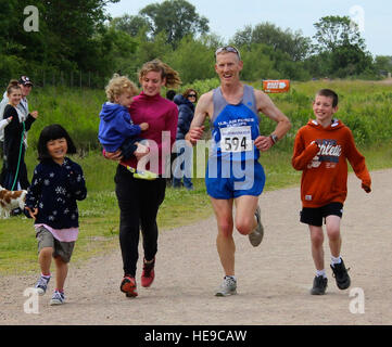 U.S. Air Force Lt. Col. Christopher Bennett, second from right, Headquarters Air Force Reservist Directorate, Air Staff, Pentagon, chief of airlift and tanker requirements, prepares to cross the finish line of the Alexander the Great half-marathon on Father's Day, June 16, 2013, at Stanwick Lakes, Northamptonshire, England. As part of a family tradition, Bennett's children - from left to right, Emma, 9; Ashton, 2; Katie Reed, 15 and Elijah, 10 - run with their dad every Father's Day. As he was running the half-marathon, and his two eldest children were running the 5 km race at the same locatio Stock Photo