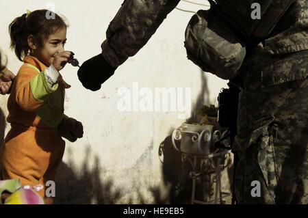 U.S. Army Staff Sgt. Joseph Faulkner of the 3rd Squadron, 7th U.S. Cavalry Regiment, 3rd Infantry Division, gives a local Iraqi girl a piece of candy as he helps conduct a dismounted patrol through a residential neighborhood in the Adhamiyah District of Baghdad, Iraq, Feb. 21, 2008. Stock Photo