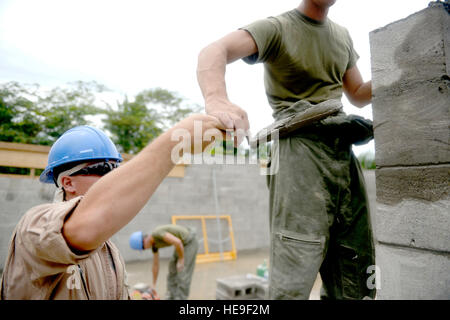 A U.S. Marine Lance Corporal Troy Matthews hands mortar to Lance Corporal Michael Dillard, both combat engineers with the 271st Marine Wing Support Squadron, 2nd Marine Air Wing, out of Marine Corps Air Station Cherry Point, N.C., while at the Gabriela Mistral primary school construction site in Ocotes Alto, Honduras, June 13, 2015. The school project is one part of the New Horizons Honduras 2015, an annual humanitarian and training exercise put on by U.S. Southern Command. New Horizons was launched in the 1980s and is an annual joint humanitarian assistance exercise that U.S. Southern Command Stock Photo