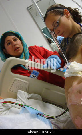 Laila Farahi (left), a female Afghan national army soldier, assists 1st. Lt. Nicole Pries(right), Intensive Care Ward nurse, deployed from the David Grant Medical Center, Travis Air Force Base, Calif., with a patient. She attended a special two-week mentorship program here at the Criag Joint Theater Hospital to work alongside U.S. doctors and nurses to hone her medical skills and get first-hand experience with trauma-based care. She was one of first women to ever attend the special program. Stock Photo