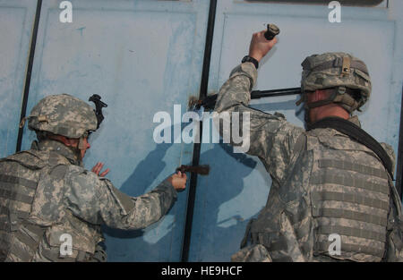 U.S. Army Staff Sgt. Joseph Carrasco and Pvt 1st Class Matthew Emerson, 2nd Battalion, 7th Cavalry Regiment, 4th Brigade Combat Team, 1st Cavalry Division, from Fort Bliss, Texas, cut the lock to a factory door in search of bomb making chemicals used in recent IED attacks on U.S forces Feb. 16, 2007 in support Operation Iraqi Freedom.( Senior Airman Vanessa Valentine)(Released) Stock Photo