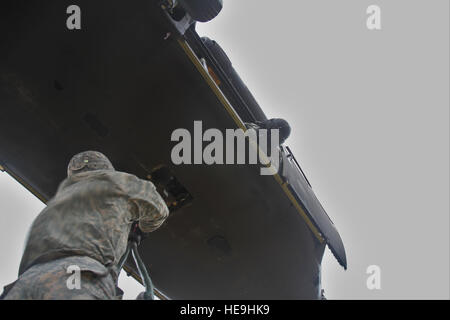 U.S. Army crew chiefs assigned to 16th Combat Aviation Brigade prepare to conduct a sling load with a UH-60 Black Hawk helicopter at Joint Base Lewis-McChord, Wash., Feb. 10, 2016. The training allowed the 16th CAB soldiers to sling load important communication equipment for the first time in their unit's history. Stock Photo