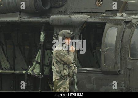 A U.S. Army crew chief assigned to 16th Combat Aviation Brigade prepares to conduct sling load operations with a UH-60 Black Hawk helicopter at Joint Base Lewis-McChord, Wash., Feb. 10, 2016. The training allowed the 16th CAB soldiers to sling load important communication equipment for the first time in their unit's history. Stock Photo