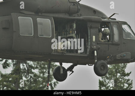 U.S. Army crew chiefs assigned to 16th Combat Aviation Brigade prepare to conduct a sling load with a UH-60 Black Hawk helicopter at Joint Base Lewis-McChord, Wash., Feb. 10, 2016. The training allowed the 16th CAB soldiers to sling load important communication equipment for the first time in their unit's history. Stock Photo