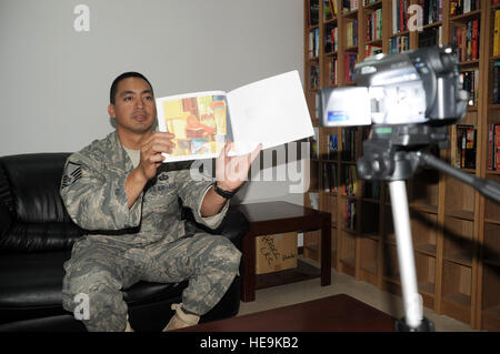 Master Sgt. Greg Ramos, services superintendent with the 380th Expeditionary Force Support Squadron, is video-recorded while reading a book for his children April 8, 2010, at a non-disclosed base in Southwest Asia. Sergeant Ramos was the second Airman at the 380th Air Expeditionary Wing to participate in the United Services Organization's United Through Reading program. The program allows for a deployed service member to read a book while being recorded and the book and a DVD is sent home to a child to see and follow along. Sergeant Ramos is deployed from the 154th Force Support Squadron at Hi Stock Photo