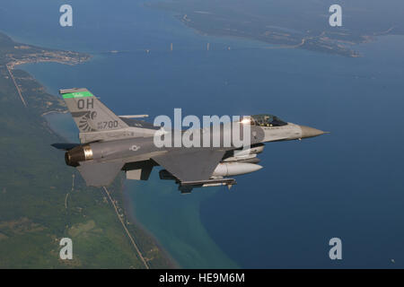 An F-16 Fighting Falcon from the 180th Fighter Wing conducts a training sortie over the Mackinac Bridge and Mackinac Island in Northern Michigan as part of a series of flight training missions over Lake Huron. Stock Photo