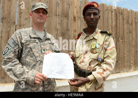 Staff Sgt. Luke Thompson holds a letter with Djiboutian army Sgt. Younis Ahmed Douleh, after the Djiboutian Soldier Recognition Ceremony, Camp Lemonnier, Djibouti, March 25, 2014. Younis wrote and carried the letter with him for five years in search of the two survivors he rendered assistance to after a helicopter crash. Thompson was the key player in ensuring the Djiboutian soldier's heroic actions were formally recognized. The Djiboutian soldiers rescued Susan Craig, a former U.S. Marine Corps pilot, and Marine Corps Maj. Heath Ruppert, Craig's co-pilot, following the Feb. 16, 2006 crash of  Stock Photo