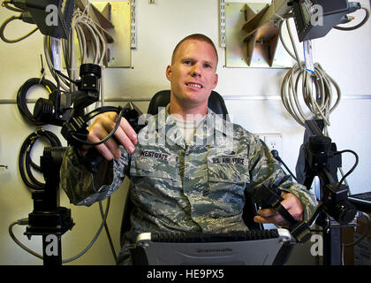 An explosive ordnance disposal technician uses a flashlight to inspect ...