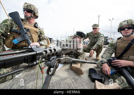 Petty Officer 2nd Class Michael Martin, Petty Officer 3rd Class Cody Castle Lt. Jeffery Kistler and Petty Officer 3rd Class Christian Walters, members of Coast Guard Port Security Unit 313 in Everett, Wash., discuss the capabilities and operation of the M2 .50-caliber machine gun during an exercise at Naval Station Everett July 22, 2015. Since PSU 313’s formal commissioning in 1998, crewmembers have been activated in support of World Trade Organization conferences, Department of Defense exercises, the response to the 9/11 World Trade Center attacks, Operation Enduring Freedom and Operation Ira Stock Photo