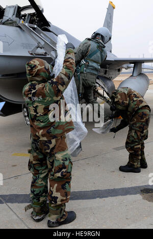 Senior Airman Clinton Caruolo, right, 8th Aircraft Maintenance Squadron, places plastic boots on Lt. Col. Jeremy Quatacker, 8th Fighter Wing chief of safety, as Senior Airman Jonathan Tiley, 8th AMXS, prepares a plastic bag to cover him from hazardous chemicals during Exercise Beverly Midnight 13-1 at Kunsan Air Base, Republic of Korea, Jan. 16, 2013. The exercise scenario demonstrated the Airmen’s capabilities to accomplish their mission in a contaminated environment. Senior Airman Marcus Morris Stock Photo