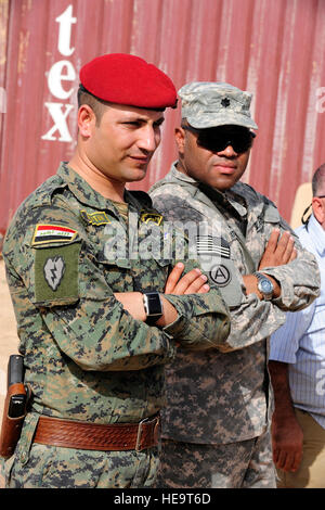 An Iraqi soldier and U.S. Solider stand together as they are briefed by Navy Explosive Ordinance Disposal  personnel during a counter improvised explosive device demonstration on Contingency Operating Base Speicher in northern Iraq, Oct. 6. The demonstration included a controlled detonation of an improvised explosive device and showed the techniques and equipment used by EOD personnel to secure, process and investigate blast sites by collection and analysis of key evidence pieces found post IED blast. Stock Photo