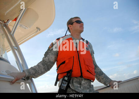 Sgt. Nick Crocker holds on while the vessel of opportunity, skips over the water during a patrol looking for oil off the coast of Mississippi. Crocker is responsible for coordinating oil search among  36 boats, streamlining communication in order to recover oil faster before it reaches shore. Some members of his unit in the Mississippi National Guard volunteered to assist with the oil response after they returned from Iraq in March. Stock Photo