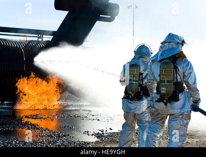 A two-person fire attack crew aims a stream of water on an aircraft fire trainer Nov. 4, 2013, at Dover Air Force Base, Del. Fire attack crews wear aircraft rescue and firefighting proximity gear for protection when battling aircraft fires. Roland Balik) Stock Photo