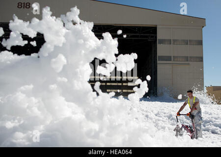 Senior Airman Allen Stoddard, 60th Civil Engineer Squadron, blows a small sea of fire retardant foam that was unintentionally released in an aircraft hangar at Travis AFB, Calif., Sept. 24, 2013. The non-hazardous foam is similar to dish soap, and eventually dissolved into liquid, which was helped by high winds. The 60th Air Mobility Wing firefighters helped control the dispersion by using powerful fans and covering drains. No people or aircraft were harmed in the incident. Ken Wright Stock Photo