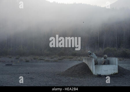 U.S. Army 1st Lt. Andres Nanez, left, throws a M67 fragmentation grenade under the supervision of Sgt. Travis Fort while conducting live fire training at Kraft Range on Joint Base Elmendorf-Richardson, Alaska, Sept. 29, 2016. In order to maintain a safe instructional environment and enforce safety standards, a ‘pit’ noncommissioned officer supervised the Soldiers who were conducting the training in the grenade pits, directing them on proper handling and use of explosives. Nanez and Fort are both assigned to Delaware Company, 1st Battalion, 501st Parachute Infantry Regiment, 4th Infantry Brigad Stock Photo