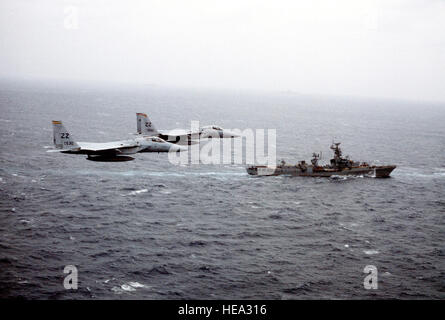 An air-to-air right side view of two F-15 Eagle aircraft from the 18th Tactical Fighter Wing as they fly near a Soviet 'Kanin' class destroyer during a tactical reconnaissance exercise. Stock Photo