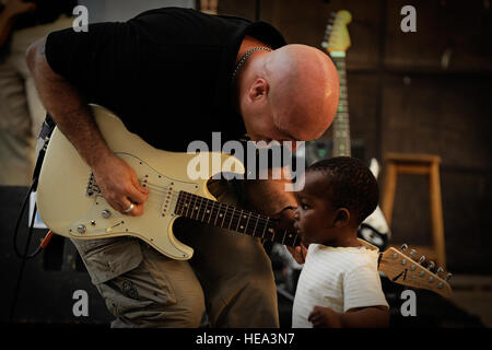 Tech. Sgt. Jason Cale, U.S. Air Forces in Europe and Air Forces Africa band guitarist, offers a child a chance to play his guitar during a concert in Dakar, Senegal, June 14, 2014, at a local cultural center. USAFE-AFAFRICA Airmen are in Senegal for African Partnership Flight, a program designed to improve communication and interoperability between regional partners in Africa. The band will be playing multiple venues in the area to inspire children and musicians through the universal language of music.  Staff Sgt. Ryan Crane) Stock Photo