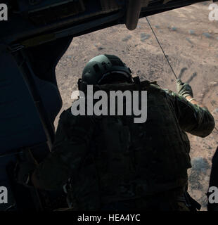 An aerial gunner with the 303rd Expeditionary Rescue Squadron observes and controls deployment of the winch from his position in an HH-60 Pave Hawk during emergency procedures and daytime tactical flight maneuvers training after taking off from Camp Lemonnier, Djibouti, July 10, 2015. The 303rd ERQS conducts training flights to maintain proficiency and provide full mission capability to users while deployed in support of humanitarian aid and contingency operations in the Combined Joint Task Force Horn of Africa area of responsibility. ( Staff Sgt. Gregory Brook/ Released) Stock Photo