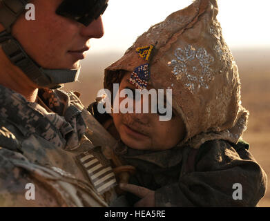 A U.S. Soldier comforts an Afghan child during a medical outreach in a Kuchi camp near Hutal, Kandahar province, Afghanistan, Jan. 5. U.S. Soldiers from 5th Stryker Brigade Combat Team, 2nd Infantry Division and members of the Afghan national police provided medical assistance and humanitarian aid to the Kuchi people living here.  Staff Sgt. Dayton Mitchell) Stock Photo