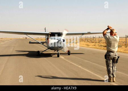 Staff Sgt. Kevin Bremmer marshals a Cessna 172 July 13 at Kirkuk Regional Air Base, Iraq.  The aircraft was flown by 2nd Lt. 'Joseph,' an Iraqi air force student pilot, and Capt. Jamie Riddle, a 52nd Expeditionary Flying Training Squadron instructor pilot. The pilots surpassed 2,000 flight training hours, marking a milestone for the Iraqi air force.  Sergeant Bremmer is deployed to the 52nd EFTS from McGuire Air Force Base, N.J., and Captain Riddle is deployed from Columbus AFB, Miss.  Airman First Class Randi Flaugh) Stock Photo