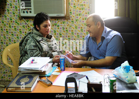 U.S. Army Sgt. Tessa Smith from Falfurrias,Texas, speaks to Fire Chief Col. Riyadh Mahmoud Khalaf about an upcoming Emergency Medical Technician course hosted by Charlie Company, 325th Brigade Support Battalion, at Contingency Operating Base Speicher, during a visit to Mujamma Fire Station, Mujamma, Iraq, July 9. The EMT course officially certifies its attendees as medically trained first responders. Stock Photo