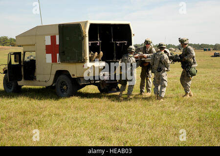 U.S. Army soldiers unload a simulated patient from the back of a M997 humvee ambulance during a field exercise at the Joint Readiness Training Center, Fort Polk, La., Oct. 15, 2012. JRTC 13-01 is designed to prepare and educate U.S. military service members for deployments to the Middle East. Stock Photo