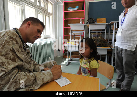 ULAANBAATAR, Mongolia – U.S. Navy doctor, Commander Steve Kriss, a member of 3rd Marine logistics, Camp Kinser, Okianwa, Japan, writes a prescription for a young Mongolian girl after a preliminary exam and discussion with her mother while at the temporary clinic held in the Buynt Uhaa Complex in Ulaanbaatar, Mongolia on Aug. 7 during Khaan Quest 2011, a combined joint-exercise hosted by the Mongolian Armed Forces in partnership with U.S. Pacific Command forces.  Khaan Quest is in its eighth year and has military participants from Canada, India, the Republic of Korea, the United States and Mong Stock Photo