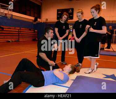 Rick Klein, kneeling, self-defense trainer, explains to Team Mildenhall women how to disarm an attacker after escaping from a knife attack Feb. 4, 2014, at the Northside Fitness Center on RAF Mildenhall, England. Klein, a former police officer, assists Linda Vu, women's self-defense trainer, by acting as an attacker in several scenarios during Vu's self-defense seminars. By substituting an attacker with himself, Klein allowed Team Mildenhall women to practice real-world techniques in a controlled environment.  Airman 1st Class Preston Webb Stock Photo