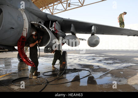 (Left to right) Cpl. Shelby Coville uses a high-pressure water spray to remove dirt and build-up residue while Cpl. Kristine Anderson holds the engine bay door open. Cpl. Karl Schmid inspects the EA-6B Prowler’s wing during a 14-day aircraft wash in Southwest Asia, September 25, 2012. Completion of a 14-day aircraft wash can average up to four hours per aircraft. Coville and Schmid are both assigned to the Marine Tactical Electronic Warfare Squadron Two and Anderson is assigned to the Marine Tactical Electronic Warfare Squadron Three. All are deployed from the Marine Corps Air Station Cherry P Stock Photo