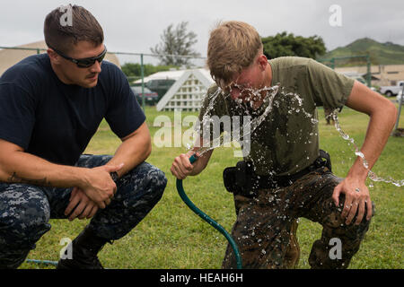 MARINE CORPS BASE HAWAII – Seaman Jake Wantland, a hospitalman with Water Front Operations, and a Tigard, Ore., native, watches Lance Cpl. Tyler Garcia, an unmanned aerial vehicle maintainer with Marine Unmanned Aerial Vehicle Squadron 3, and a New York Mills, N.Y., native, as he washes his face after a defensive and offensive tactics course near the Provost Marshal’s Office aboard Marine Corps Base Hawaii, Aug. 18, 2016. Marines from various units are undergoing a two-week training course to support the PMO as part of the Gate Augmentation Force.  One of the training requirements necessary fo Stock Photo