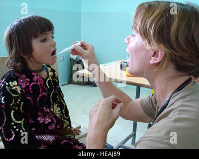 U.S. Navy Lt. Karen Nordine checks the temperature of a young Afghan patient during a village medical outreach in Shinkay District. Capt. Bob Everdeen) Stock Photo