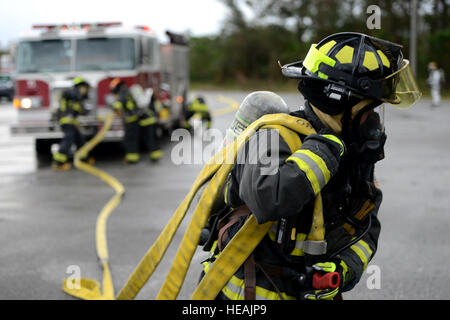 A Kadena firefighter from the 18th Civil Engineer Squadron drags a fire hose during a simulated burning vehicle accident as part of a mission focused exercise on Kadena Air Base, Japan, Dec. 2, 2014. The MFE is designed to train Airmen on proper techniques and procedures for an array of scenarios from chemical attacks to mass casualties.  Senior Airman Maeson L. Elleman Stock Photo