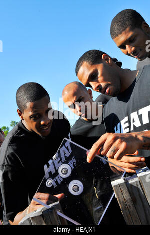Miami HEAT players (left to right), Mario Chalmers, Carlos Arroyo, Eddie House, and Dexter Pittman, examine the bullet holes in a piece of tempered glass after the Dynamics of International Terrorism demonstration at Hurlburt Field, Fla., Sept. 30, 2010. The HEAT took time from their 2010 Training Camp to tour Hurlburt Field and learn about the Air Force Special Operations Command’s mission.  U.S. Air Force Senior Airman Sheila deVera/) Stock Photo