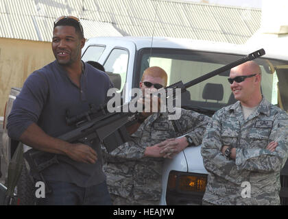 Michael Strahan, announcer with Fox NFL Sunday, handles a M107 long-range rifle while visiting the 755th Air Expeditionary Group's Explosive Ordnance Disposal flight Nov. 6, 2009, at Bagram Airfield, Afghanistan.  Senior Airman James Dobrynski (left) and Staff Sgt. Thomas Vaught look on. The NFL Sunday team of Curt Menefee, Terry Bradshaw, Howie Long, Michael Strahan, Jimmy Johnson and Jay Glazer are scheduled to broadcast live Nov. 8 from here as a tribute to the dedication of America's servicemembers.  Senior Airman Felicia Juenke) Stock Photo