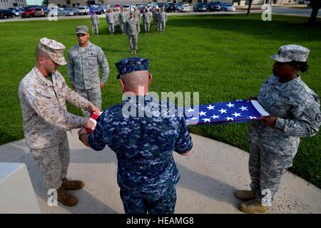 (From left) U.S. Marine Corps Cpl. Landon Beaty, U.S. Navy Petty Officer 1st Class Whitney Sloane, and U.S. Army Sgt. 1st Class Crystal Seymore fold the U.S. flag after lowering it during a retreat ceremony at Dover Air Force Base, Del., Sept. 6, 2013. The three service members are assigned to Air Force Mortuary Affairs Operations and carried out the multi-service retreat ceremony along with U.S. Air Force Staff Sgt. Alex Stoica who is also assigned to AFMAO. Military members from both AFMAO and the Armed Forces Medical Examiners System stood in formation during the retreat to render their res Stock Photo