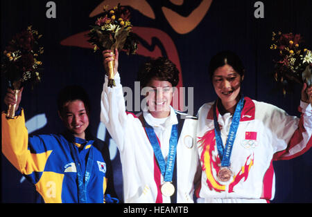 000916-F-8217W-006 Gold medalist Nancy Johnson (center) of the U.S., raises her hands with silver medalist Cho-Hyun Kang (left), of Korea, and bronze winner Jing Gao (right), of China, during the medal ceremony for the womenÕs 10 meter air rifle competition at the 2000 Olympic Games in Sydney, Australia, on Sept. 16, 2000. JohnsonÕs gold medal is the first awarded in the Sydney Games and the first gold for the U.S.  Johnson is married to U.S. Army Staff Sgt. Ken Johnson, who is also on the U.S. Olympic shooting team.   Tech. Sgt. Robert A. Whitehead, U.S. Air Force.  (Released) Stock Photo