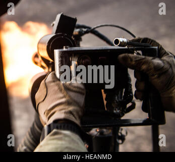 An aerial gunner with the 303rd Expeditionary Rescue Squadron arms fires weapon flying in a UH-60 while conducting live fire weapons training working with Joint Tactical Air Controllers from Detachment 1, 82nd Expeditionary Rescue Squadron at the Arta range, Djibouti, June 22, 2015. The 303rd ERQS conducts training events working with enabling units to maintain proficiency while deployed in support of humanitarian aid and contingency operations in the Combined Joint Task Force Horn of Africa area of responsibility. ( Staff Sgt. Gregory Brook Stock Photo