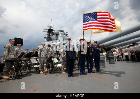 The New Jersey National Guard Color Guard and soldiers of the 63rd Army Band stand at attention during the singing of the national anthem by the USO Liberty Bells on board the Battleship New Jersey, located at Camden, N.J., June 3, 2012.  Soldiers and airmen of the New Jersey National Guard along with their families, as well as sailors from Naval Weapons Station Earle and residents from Veterans Memorial Home at Menlo Park were treated by Jersey Mike's Subs to Christmas in July. After remarks by Brig. Gen. Michael L. Cunniff, the Adjutant General and Lt. Gov. Kim Guadagno, there were performan Stock Photo