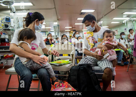 SUBIC BAY, Philippines (Aug. 8, 2015) A Filipino family waits to check in to patient receiving aboard the hospital ship USNS Mercy (T-AH 19) during Pacific Partnership 2015.  Operation Smile conducted patient selection, logistics, and surgery for children with cleft palate and cleft lip. Mercy is currently in the Philippines for its third mission port of PP15. Pacific Partnership is in its tenth iteration and is the largest annual multilateral humanitarian assistance and disaster relief preparedness mission conducted in the Indo-Asia-Pacific region. While training for crisis conditions, Pacifi Stock Photo