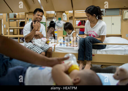 SUBIC BAY, Philippines (Aug. 8, 2015) A Filipino family sits in a pre-operation ward aboard the hospital ship USNS Mercy (T-AH 19) during Pacific Partnership 2015.  Operation Smile conducted patient selection, logistics, and surgery for children with cleft palate and cleft lip. Mercy is currently in the Philippines for its third mission port of PP15. Pacific Partnership is in its tenth iteration and is the largest annual multilateral humanitarian assistance and disaster relief preparedness mission conducted in the Indo-Asia-Pacific region. While training for crisis conditions, Pacific Partners Stock Photo