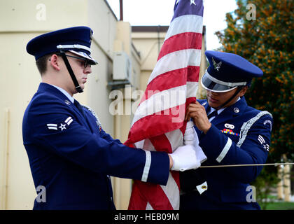 U.S. Air Force Airman 1st Class Roger Lanoie and Senior Airman Juanita Stewart, 31st Fighter Wing Honor Guard members, remove the Prisoner of War/Missing in Action flag during the remembrance week’s retreat ceremony Sept. 17, 2015, at Aviano Air Base, Italy. The Air Force Sergeants Association hosted several events during the week, including a vigil run and table ceremony to remember fellow service members.  Senior Airman Areca T. Bell Stock Photo