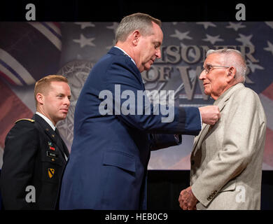 Air Force Chief of Staff Gen. Mark A. Welsh III presented the Prisoner of War Medal to 1st Lt. Paul Gambaiana during a ceremony in the Pentagon, April 30, 2014. Gambaiana, and seven other aviators, all bomber crew members, were shot down flying missions over Germany and were held in a prison camp in Wauwilermoos, Switzerland. The men were originally denied POW status. U.S. Army Maj. Dwight Mears (looking on from the left), whose grandfather Lt. George Mears, who was held at the prison, fought diligently for 15 years to get the men recognized as POWs. Then Acting Secretary of the Air Force Eric Stock Photo