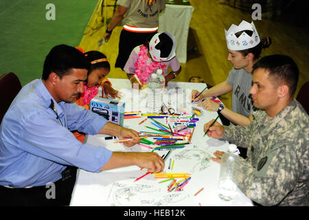 Iraqi police officers, Iraqi children from the Tikrit Orphanage and U.S. Soldiers enjoy coloring activities during a fun filled day at the Community Project for Tikrit Orphanage, hosted by the 25th Special Troops Battalion, 25th Infantry Division, at Contingency Operating Base Speicher, Iraq, June 30. The event set an example of community service and showed commitment to those affected by the violence in Iraq. Stock Photo