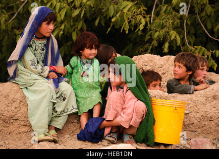 Afghan children watch U.S. Soldiers and Airmen as they pass through their village during a dismounted patrol near Forward Operating Base Lane, Zabul Province, Aug. 6. U.S. forces assisted the local Afghan National Police in a humanitarian assistance visit to give shoes to children in Arghandab District. Stock Photo