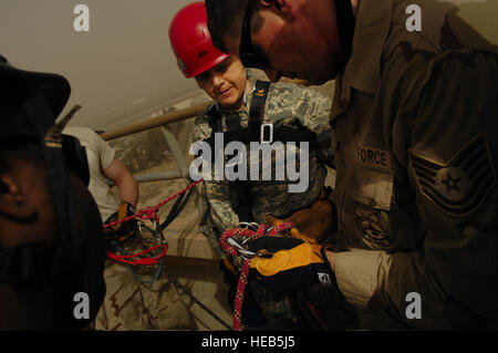 Tech. Sgt. Tracy McDonald , Air Traffic Controller, 447 Expeditionary Operations Support Squadron, Sather Air Base, Iraq is briefed by Tech. Sgt. Ed Autery, 447 Expeditionary Civil Engineer Squadron, Fire Department, before rappelling from the Baghdad International Airport air traffic control tower on March 3. The training is necessary in case personnel working in the 185-foot tower  need to escape during an emergency. Tech. Sgt. Jeffrey Allen) Stock Photo