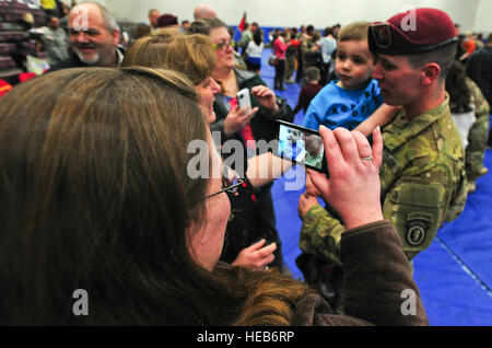 Lisa Musick, left, takes video with her cellphone of Sgt. James Anderson, a native of Charlotte, Mich., as he holds his son Kaleb, 3, during a redeployment ceremony at Buckner Physical Fitness Center on Joint Base Elmendorf-Richardson. Nearly 100 U.S. Army Alaska soldiers returned home Thursday evening, March 14, from a nine-month deployment to the southern provinces of Afghanistan in support of Operation Enduring Freedom. The soldiers are assigned to the 23rd Engineer Company, part of the 2nd Engineer Brigade home based at Joint Base Elmendorf-Richardson. During their deployment, the soldiers Stock Photo