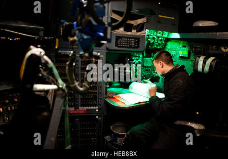 YOKOTA AIR BASE, Japan -- Airman 1st Class Stephen Tessier, 374th Aircraft Maintenance Squadron flying crewchief, reviews log books while powering up a C-130 Hercules here March 14. C-130s play a crucial role in disaster relief due to their ability to land on dirt runways and other less-than-ideal landing conditions. Staff Sgt. Samuel Morse) Stock Photo