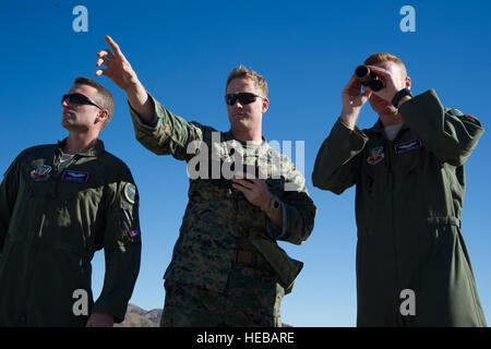 U.S. Air Force Capts. Ryan Rutter, left, and Matthew C. Barrett, right, both pilots with the 354th Fighter Squadron, look on as U.S. Marine Gunnery Sgt. Daniel Haack, air support operations operator, Tactical Training Exercise Control Group, Marine Air Ground Task Force Training Command, gestures toward an attack target while participating in Integrated Training Exercise 2-16 at Marine Corps Air Ground Combat Center, Twentynine Palms, Calif., Jan. 26, 2016. MCAGCC conducts relevant live-fire combined arms, urban operations, and joint/coalition level integration training that promote operationa Stock Photo